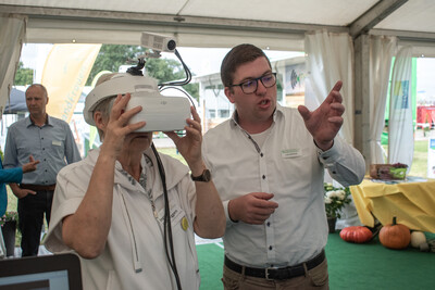 Luka Backhus führt einer Messebesucherin die Kuh-VR-Brille am LWK-Messestand auf der LandTageNord vor